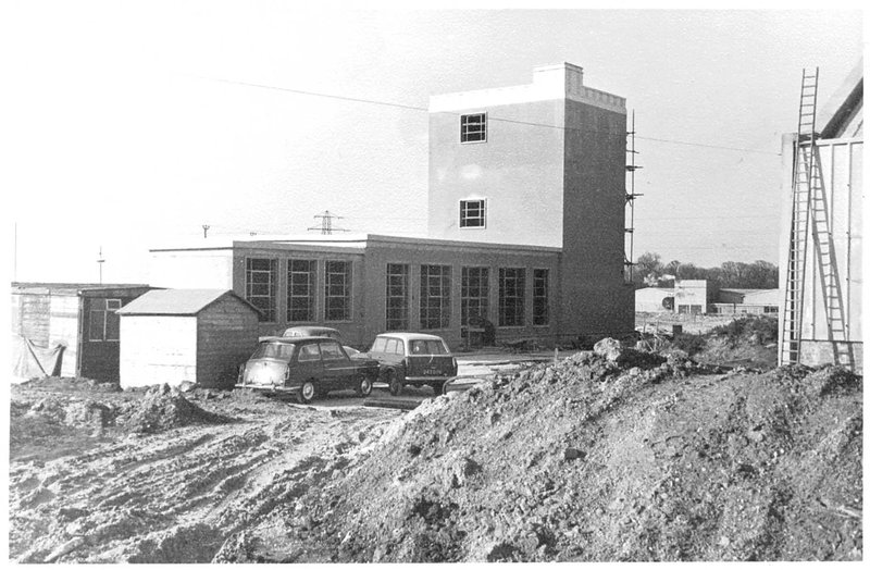 Office and administration building under construction with 1960s vehicles
